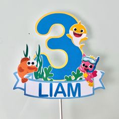 a cake topper with the number three on it and some cartoon characters around it