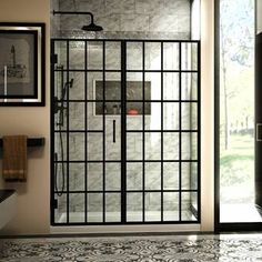 a glass shower door in a bathroom with tile flooring and black trim on the walls