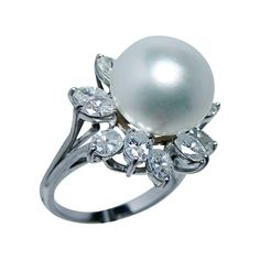 This is a very high quality 18K yellow gold pearl and diamond ring. Featured is a creamy white 12.9 x 12.6mm genuine pearl with a high luster set in the center. Just extraordinary!! The pretty design hosts 12 brilliant oval cut diamonds for a total weight of 2.40 carats. They are very high quality diamonds estimated to be clean VS-1-2 in clarity and GH in color (near colorless). Very white diamonds!! They create a fantastic halo around the pearl! These fascinating gems are set in a gorgeous moun Formal White Diamond Ring With Pearl Drop, Luxury Diamond Rings With Pearl Drop, Luxury White Rings With Pearl Drop, White Akoya Pearl Rings With Diamond Accents, Luxury White Pear-shaped Diamond Ring, White Pearl Diamond Ring With Pearl Drop, White Diamond Pearl Drop Ring, White Pearl Ring With Diamond, Elegant Oval Pearl Ring With Brilliant Cut