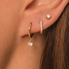 a close up of a person's ear with two small diamond earrings on it