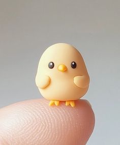 a tiny toy bird sitting on top of a finger