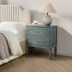 a bedroom with a bed, nightstand and lamp on the end table next to it