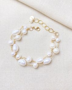 Make a classic and elegant statement with this multi-layered mixed pearl bracelet. Two handcrafted strands of differently shaped and sized pearls create a versatile accessory suitable for weddings, brunches, work, and more. The lobster clasp and extender ensure a secure and adjustable fit. Length: 7.5 inches plus 1.5-inch extender Materials: gold fill, cultured freshwater pearls GIFTING ~ Jewelry gift box included. ~ I am happy to ship directly to the recipient.  Enter their address during check Wedding Baroque Pearl Chain Bracelet, Pearl Beaded Bracelets With Pearl Charm For Wedding, White Pearl Chain Bracelet For Wedding, Wedding Bracelets In Pearl White Baroque Pearl, Baroque Pearl Bracelets For Wedding, Pearl White Baroque Pearl Bracelets For Wedding, Wedding Baroque Pearl Bracelets In Pearl White, Baroque Pearl Wedding Bracelets, Pearl White Bracelet With Pearl Charm For Wedding