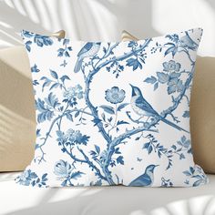 a blue and white pillow sitting on top of a couch next to a wall with flowers