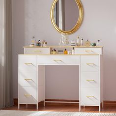 a white vanity with gold accents and a round mirror on the wall above it in a room