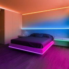 a bed with purple and blue lights on the wall next to it in a bedroom