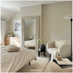 a bedroom with a bed, chair and mirror on the wall next to each other