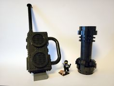 a lego figure next to an old fashioned radio and canister on a white surface