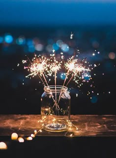 a glass jar filled with fireworks on top of a wooden table