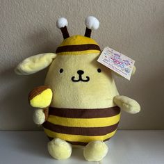 a yellow stuffed animal with a brown and white bee on it's chest, holding an ice cream cone