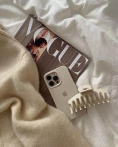 an iphone case sitting on top of a bed next to a hair comb and magazine