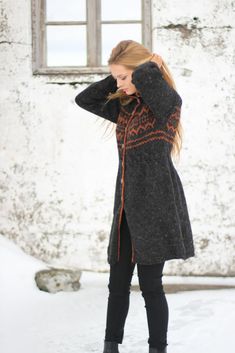 a woman standing in front of a window with her hands on her head and wearing black boots