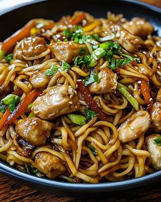 a close up of a plate of food with noodles and chicken in it on a table