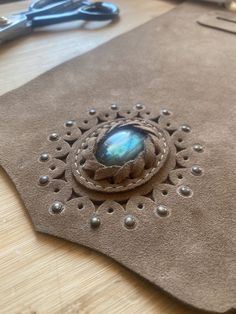 a close up of a piece of leather on a table with scissors and other items