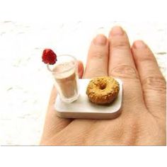 a miniature donut on a tiny plate with a glass of milk and a strawberry