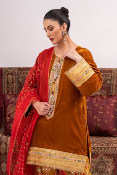 A traditional style suit in velvet with gota work on the neck and hem with handmade motifs on the neckline. Paired with a tailored shalwar and an emroidered organza dupatta for a sophisticated look.3-piece suitReady-to-wear Gold Salwar Kameez With Embroidered Border For Designer Wear, Designer Red Churidar With Embroidered Border, Traditional Formal Lawn Suit With Dupatta, Traditional Lawn Suit With Mirror Work In Dola Silk, Traditional Lawn Suit With Mirror Work For Formal Occasions, Traditional Formal Lawn Suit With Mirror Work, Traditional Lawn Suit With Mirror Work For Formal Events, Designer Jamawar Anarkali Set With Embroidered Border, Traditional Festive Lawn Suit With Mirror Work