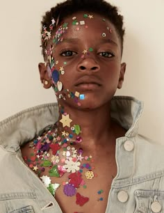 a woman with her face covered in buttons and confetti on her chest is looking at the camera