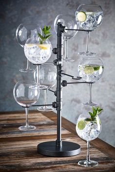 an assortment of wine glasses with limes and ice in them on a wooden table