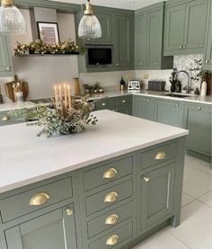 a kitchen with green cabinets and candles on the counter top in front of an oven