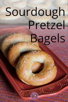 three bagels sitting on top of a red tray with sesame seeds in them and the words sourdough pretzel bagsel