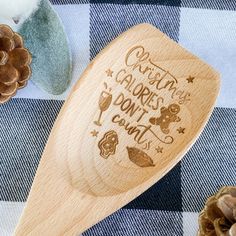 a wooden spoon sitting on top of a blue and white checkered table cloth next to pine cones