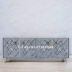 the sideboard is decorated with black and white geometric designs, which are accented with brass handles