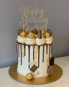 a birthday cake with white frosting and gold decorations