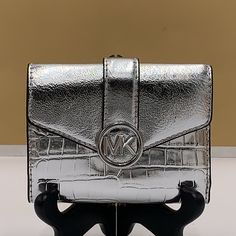 Michael Kors Carmen Medium Faux Leather Wallet Silver Crocodile Print Pattern Nwt Authentic Reimagined In A Shrunken Silhouette From Faux Leather, This Wallet Version Of Our Beloved Carmen Bag Will Stylishly Keep Your Essentials Within Arm’s Reach. Featuring A Foldover Closure And Our Iconic Charm, It’s As Polished As It Is Practical. Wallet Faux Leather 88.92% Coated Canvas/11.08% Polyester Gold-Tone Hardware 4.75"W X 3.75"H X 1.25"D Exterior Details: Back Slip Pocket Interior Details: 2 Back Z Michael Kors Leather Bifold Bag, Luxury Michael Kors Bifold Bags, Michael Kors Leather Bags With Card Slots, Michael Kors Clutch With Card Slots, Rectangular Travel Wallets With Silver-tone Hardware, Travel Wallets With Silver-tone Hardware, Michael Kors Daily Use Bag, Michael Kors Silver Rectangular Shoulder Bag, Exterior Details