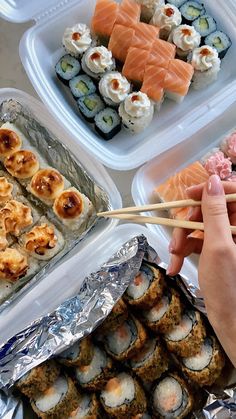 sushi is being served in plastic containers with chopsticks