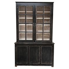 an old black china cabinet with glass doors and shelves on the front, isolated against a white background