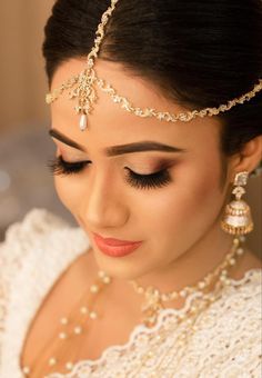 a woman in a white dress wearing a gold headpiece and pearls on her hair