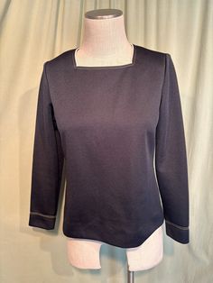 This is a sweet vintage top from the 70s.  Labeled My Latest Leslie Fay. No size tags. The bust measures 38", see measurements below. This classic top is made of black polyester. It has beige trim around the square neckline, along with double rows of beige top stitching. The same stitching trims the sleeve cuffs. It is a pullover top that zips down the back with a nylon zipper.    The top is in very good condition!  No damage or soil. Super cute!  If you have never worn vintage before, please measure yourself!! Vintage sizes run smaller than today's sizes, know your measurements before buying! Bust measured from side seam to side seam at the underarm: 18" for a 36" bust Waist measured from side seam to side seam at hem: 19" for a 38" hemline Shoulders: 14" Length measured from shoulder to Vintage Black Office Tops, Vintage Black Office Top, Retro Long Sleeve Office Tops, Retro Black Tops For Work, Retro Fall Workwear Tops, Retro Fall Office Tops, Beige Trim, Vintage Blouses, Please Me