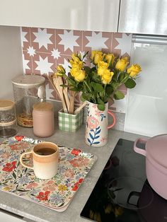 a kitchen counter with yellow flowers in a vase on the stove top and other cooking utensils