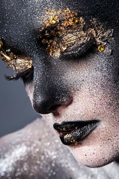 a woman with black and gold makeup on her face