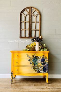 a yellow dresser with flowers painted on it