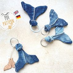 three pieces of blue jean fabric with metal rings attached to them, on a white surface