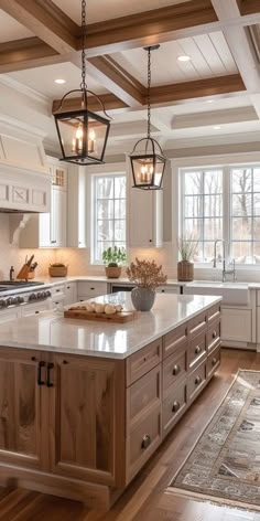 a large kitchen with an island in the middle and two hanging lights above it on the ceiling