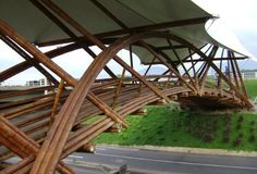 a large wooden structure sitting on the side of a road next to a lush green field