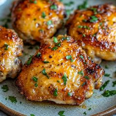 four pieces of chicken on a plate with parsley sprinkled around it's edges