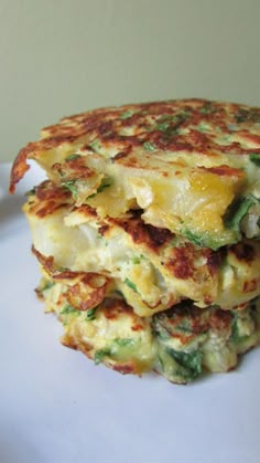 a stack of food sitting on top of a white plate covered in cheese and broccoli