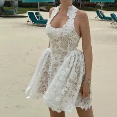 a woman standing on the beach in a white dress