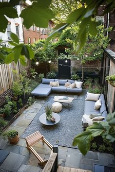 an outdoor living area with couches, tables and plants in the back yard at dusk