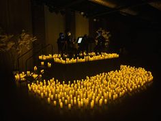 many candles are arranged in the shape of a heart on a black surface with music instruments behind them