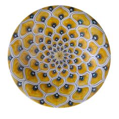 a yellow and white plate with an intricate design on the top, in front of a white background