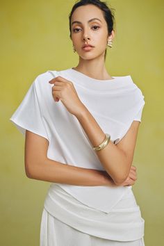 a woman in a white dress posing for a photo with her hand on her hip