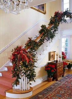 a staircase decorated for christmas with garland and poinsettis on the banister