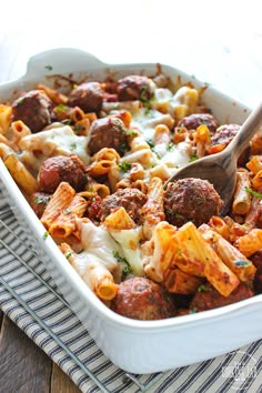 a casserole dish with meatballs and pasta in it on a striped cloth