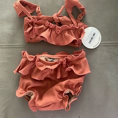 The Mini Cabana Bikini Set Is In Coral And Size 12-18 Months. Baby Size.A Take On Montce’s Classic Cabana Top But For Minis. We Hit All The Same Details- Created A Well-Made Bikini Set With Ruffle Detail, Cap Sleeves, Adjustable Straps + Scrunched Waistband For Comfort. Available In All Baby Sizing Only. Baby Bikini Top Style Details: Ruffle Front Detailing Adjustable Cap Sleeves Tie Back Closure Matching Baby Swim Bloomer Style Details: Bottom Designed For Diaper Wearing Children Mini Ruffle Sk Summer Beachwear Tankini For Playtime, Summer Beachwear Tankini, Playful Beach Sets With Ruffles, Playful Ruffled Beach Sets, Playful Ruffled Beach Set, Beach Season Ruffled Swimwear, Summer Sleeveless Tankini For Playtime, Sleeveless Summer Tankini, Fitted Beachwear Tankini For Playtime