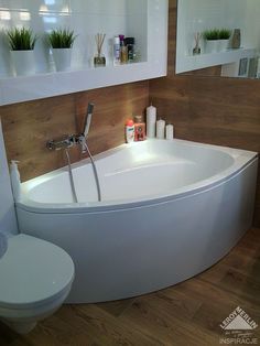 a white bath tub sitting in a bathroom next to a toilet and wall mounted shelves