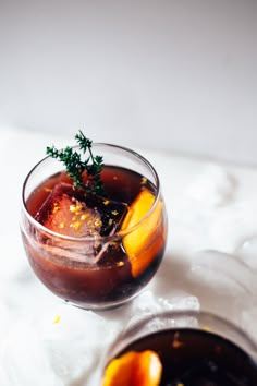 two glasses filled with drinks sitting on top of a white tablecloth next to each other